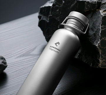 Titanium Travel Bottle with a brand logo on a rock and sand background