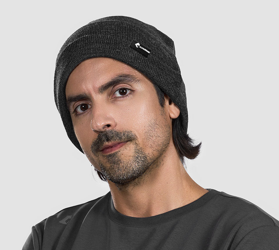 Man wearing a Dark Grey Merino Wool Beanie with a logo on a light gray background
