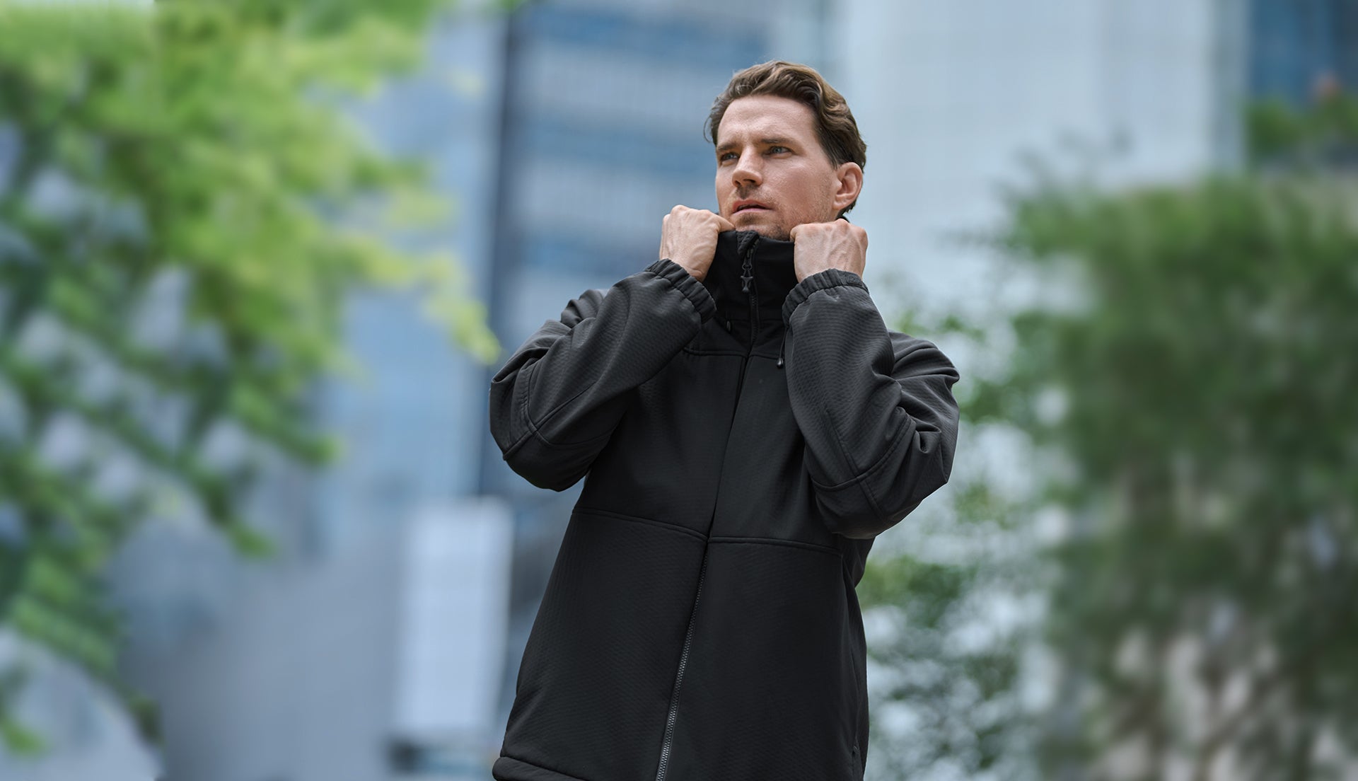 Man wearing a black jacket in an urban setting with blurred background